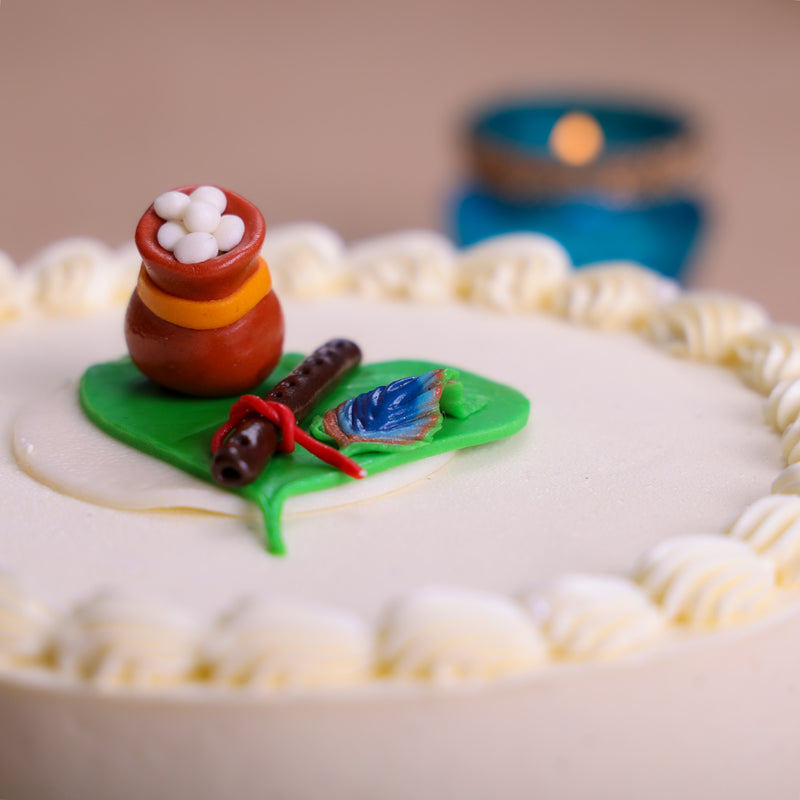 The pot and the flute atop this Krishna Janmashtami birthday cake  is nestled in the symbolic green betel leaf that lord Krishna used to teach Bhima a lesson.This is one of the most special Krishna cakes that we crafted to make your Janmashtami unforgettable.