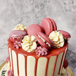 A dark pink frosting coats the top of this elegant cake with macaroons and gracefully drips down the sides. This is a rather tall, fancy birthday cake for him/her whose heightened base comes in a delicious shade of pale yellow and ornamented with a few more of those gold pearls.