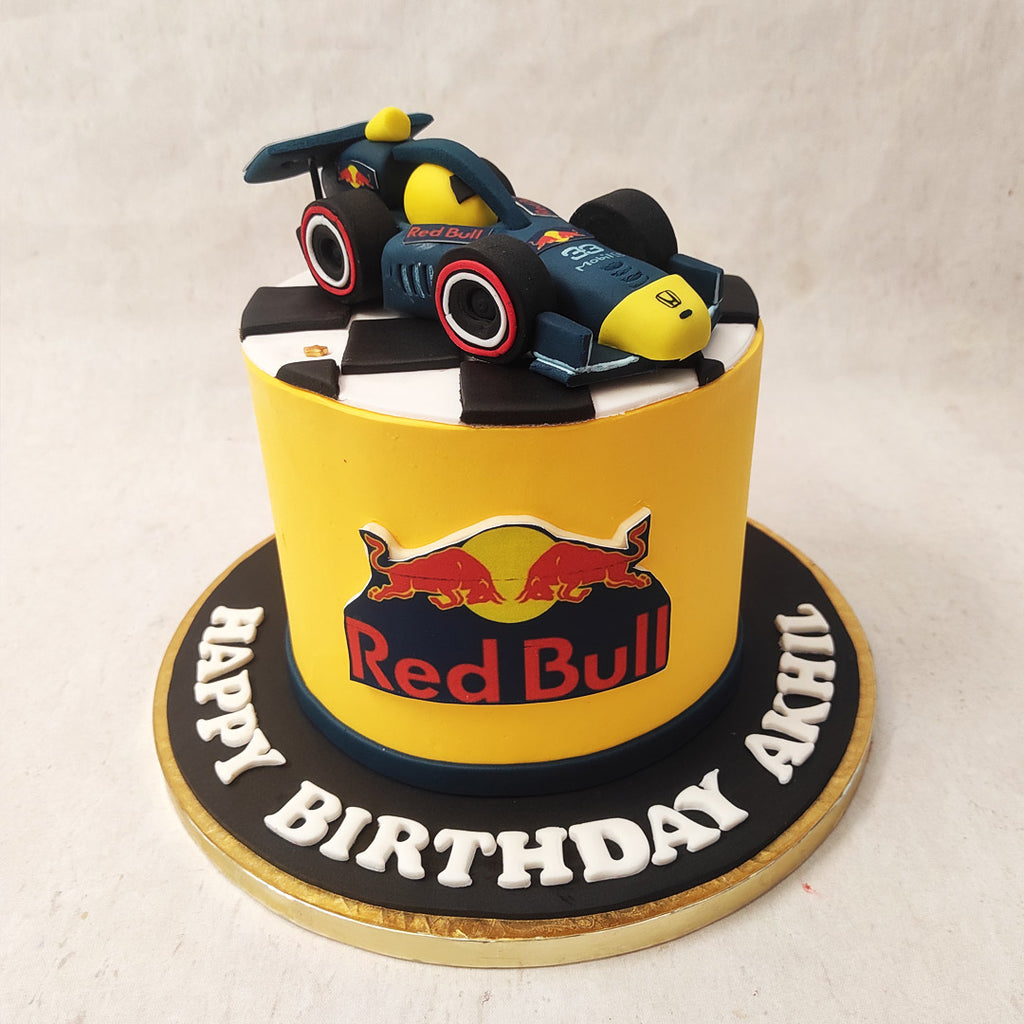 Featuring a tall yellow base, the kind that instantly reminds you of world-famous events, this sports car cake features a realistic Redbull logo around the circumference.
