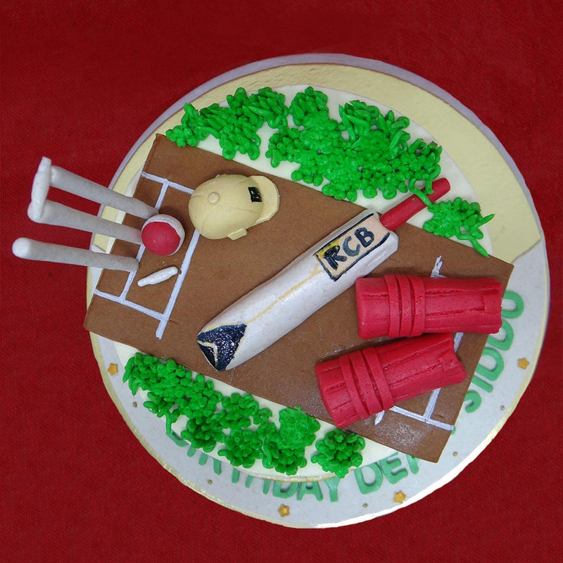 The top of this multi-colored cricket cake for her/him is laid on a pitch, complete with white stumps, red cricket pads, a bat and green turf. The logo of the rcb cake design has the bold pride and the challenger spirit and unleashes the lion in all the cricket fans.'