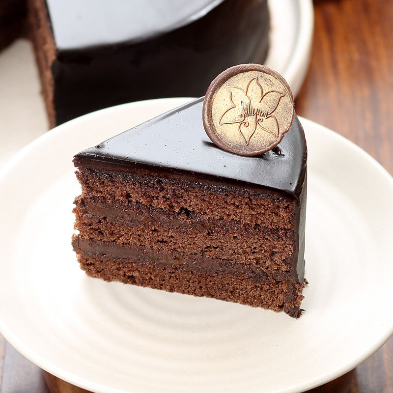 Cut view of sacher torte cake which shows the thick sponge and apricot mixed chocolate cream filled between the sponge 