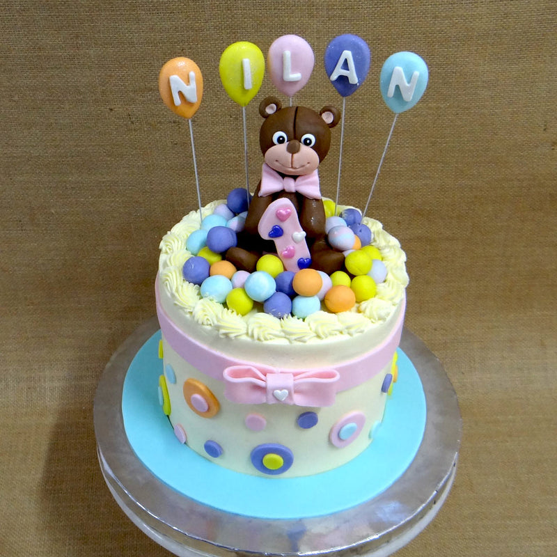 Teddy bear cake with balloon on top of the cake and cute teddy bear sitting on this colourful birthday cake
