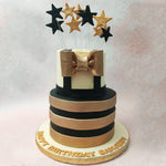 This two tier tuxedo cake with black and gold stars resembles a statement piece on display in a mall or at a fashion show, with the bottom tier being akin to the revolving stage and the top tier representing the tuxedo around which the rest of this design is inspired.