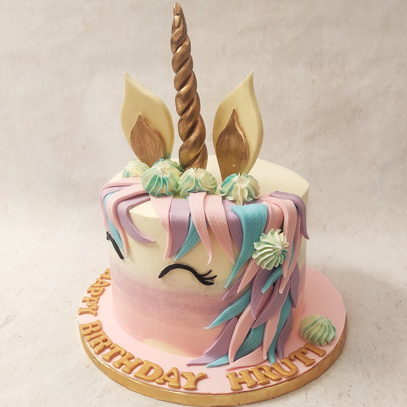 The mane on this Unicorn theme birthday cake for kids is made out of pastel pink, purple and blue fondant and the golden ears on top matching the magical gold horn