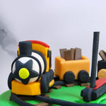 The heart of this toy cake, however, is the orange toy train on top comprising a life-like steam engine and two freight wagons carrying tiny bricks of chocolate inside. This is a train cake design with a twist as at the center of the chocolate-laiden track, a toy scooty is proudly displayed, a felicitous asset to one’s 6th birthday cake with a variety of elements that 6-year olds truly cherish