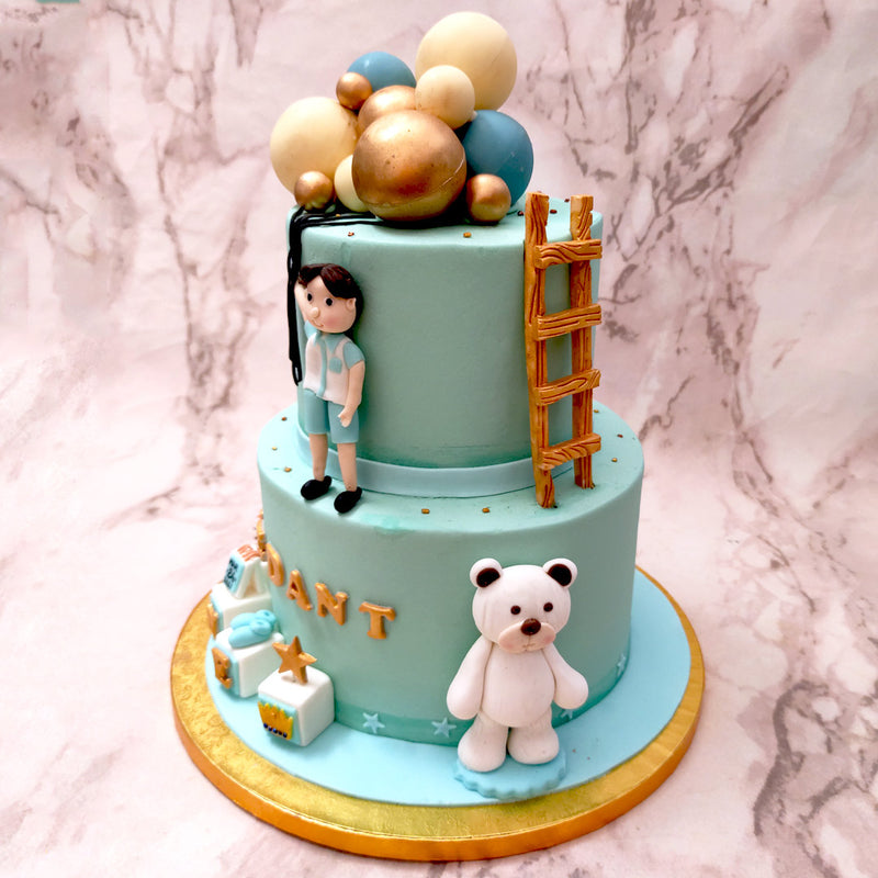 This balloon cake design for boys highlights a young boy floating away on some beautiful white, gold and blue balloons that garnish the top of this boy with balloon cake. Like a bunk bed, a ladder can also be found on the side leading from the bottom tier to the top tier. 