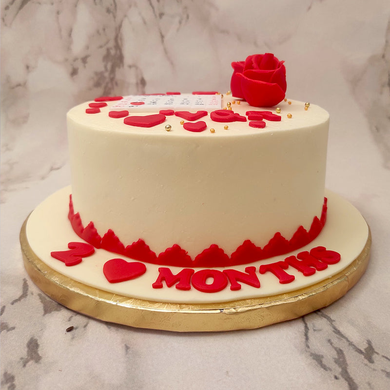 Red buttercream roses have been piped onto this anniversary calendar cake with an edible calendar pasted in the middle showcasing the happy lot's special month and D-day marked off in a red heart.