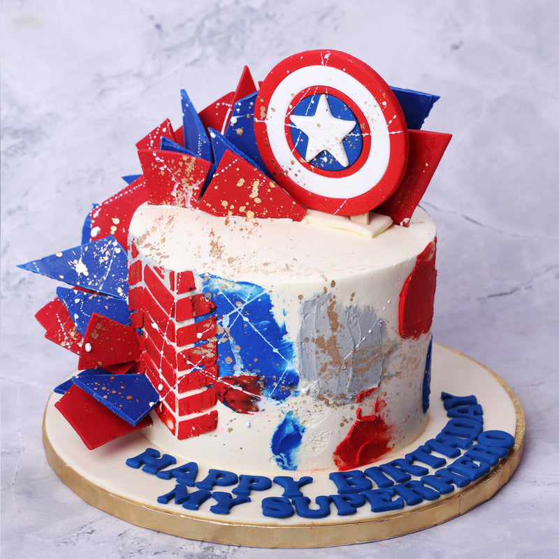This Captain America theme cake is a three dimensional masterpiece, centering around the blue, red and white theme of this Superhero. With a neutral white base forming the body of this Captain America birthday cake for her / Captain America birthday cake for him, the popular Captain America shield that is commonly seen in the films and comic books can be seen ornamenting the top. 
