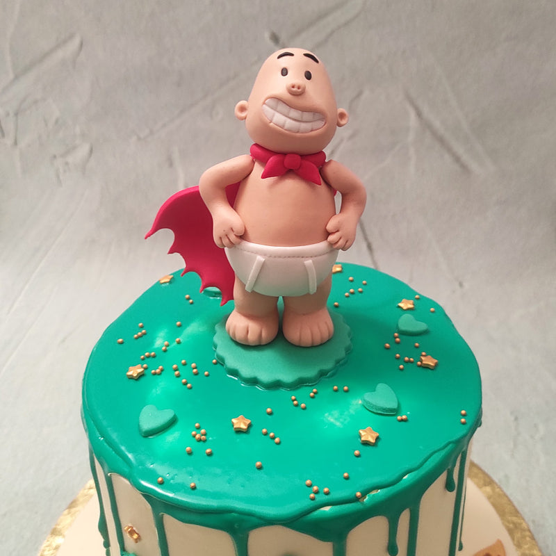 The simple white base of this Captain Underpants birthday cake for kids is complemented by the green drip pattern coating the top and the heart and gold stars embellishing it. However, the real show stopper is the Captain Underpants cake topper: an edible figurine of Captain Underpants himself. 