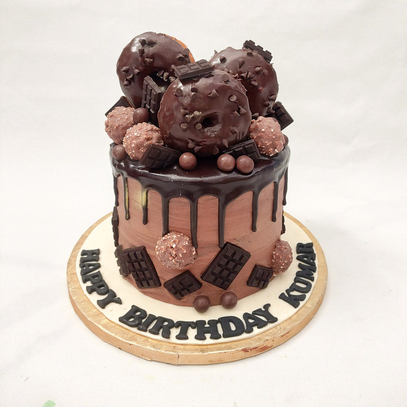Welcome to your very own sugar-coated world presented to you in the form of this chocolate donut drip cake. This chocolate donut cake design is for those with a sweet tooth and a taste for the flamboyant.