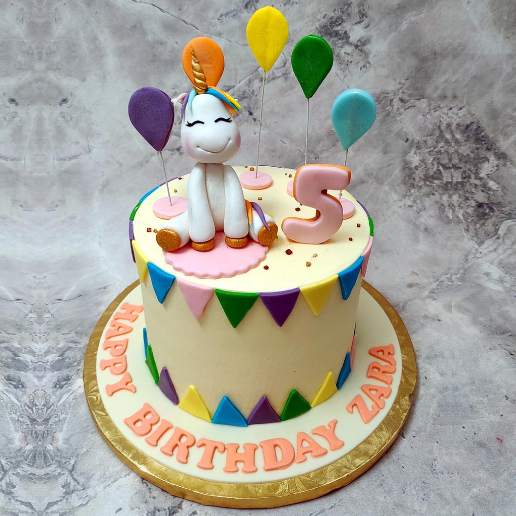 Here's a colorful unicorn cake adorned with so many festive elements, it's fitting to be the centerpiece at the feast of a king. This unicorn cake with balloons was crafted to serve up some fairytale magic on a golden platter in real life.