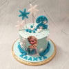 This Frozen Elsa cake has a blue base that comes embellished with sugary, white and blue snowflakes and snowballs.  Braided strands of blue fondant ribbon the base of this Else theme cake design and come to a point centered by Elsa herself made to look like a poster cut-out or print out.
