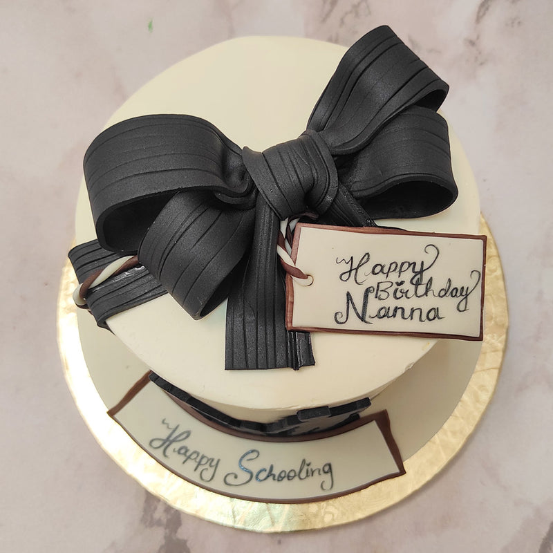 The highlight of this family theme cake is the silhouette on its circumference which showcases a mother and father holding the hand of their little one. Artistic and abstract smears of buttercream create the background of them being in a bustling street and dropping the child off to school.