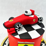 One of these items is the edible Ferrari logo plate lying in the centre of this F1 theme cake against a light, neutral-toned background that highlights the colour of all the elements here. 