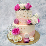 This two tier cake comes in a classy marbleized colour of off-white, decorated with tiny edible pearls and gold leaves. Smeared onto this floral cake in textured layers is pink buttercream that follows the pink and white colour palette set by the roses embedded into this wedding cake.