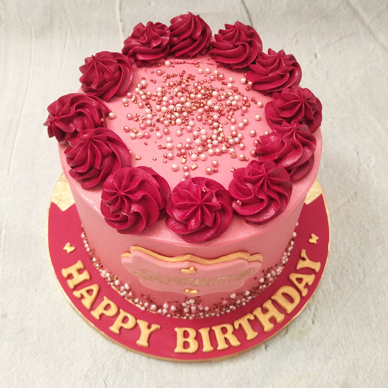  A tall base coated in velvety buttercream frosting with a smooth finish forms the body of this maroon colour cake. Edible, lustrous beads in pink, white and bronze colours embellish this entire maroon colour cake design in a way similar to how a ballroom looks after a confetti shower. This adds to the luxe look of this maroon buttercream cake design.