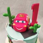  The top tier of this Lightning McQueen cake features a southern setting, similar to one seen in the film with cacti and a traffic signal displayed near some barren land as fluffy white clouds float on by. Lightning McQueen himself can be seen stationed on top by some cacti and with his proud , victorious no. 1 displayed right next to him. 