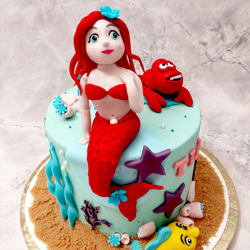 Drawing inspiration from the famous Disney story 'The Little Mermaid', this mermaid theme birthday cake for kids incorporates a clown fish at the bottom and a lovely, red crab at the top.