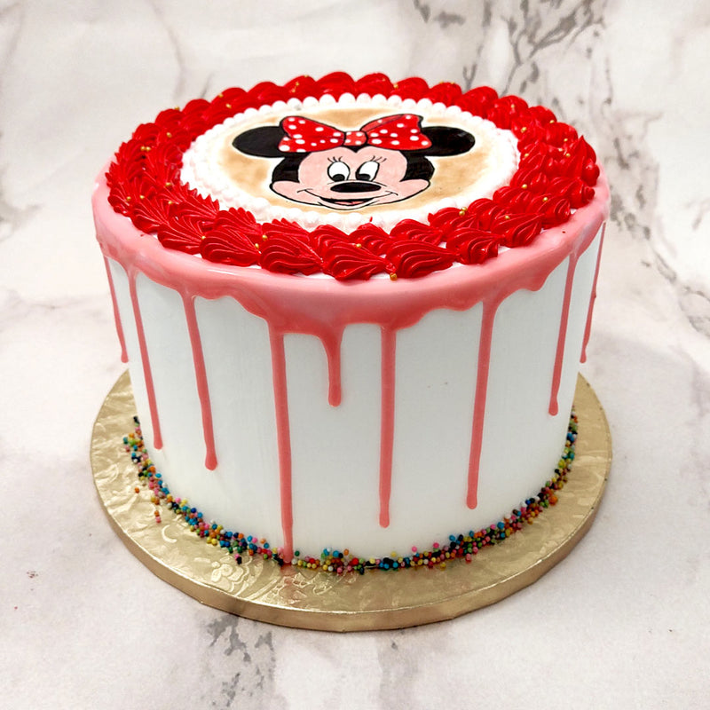 Since Minnie has been dressed in a very human way with white gloves, a red / pink and white polka-dotted bow, the colour scheme of this Minnie Mouse cake design follows the same patterns. Minnie Mouse’s face has been hand painted in the centre of this Minnie Mouse theme cake aner her portrait has been bordered with a string of lustrous and edible white pearls. 