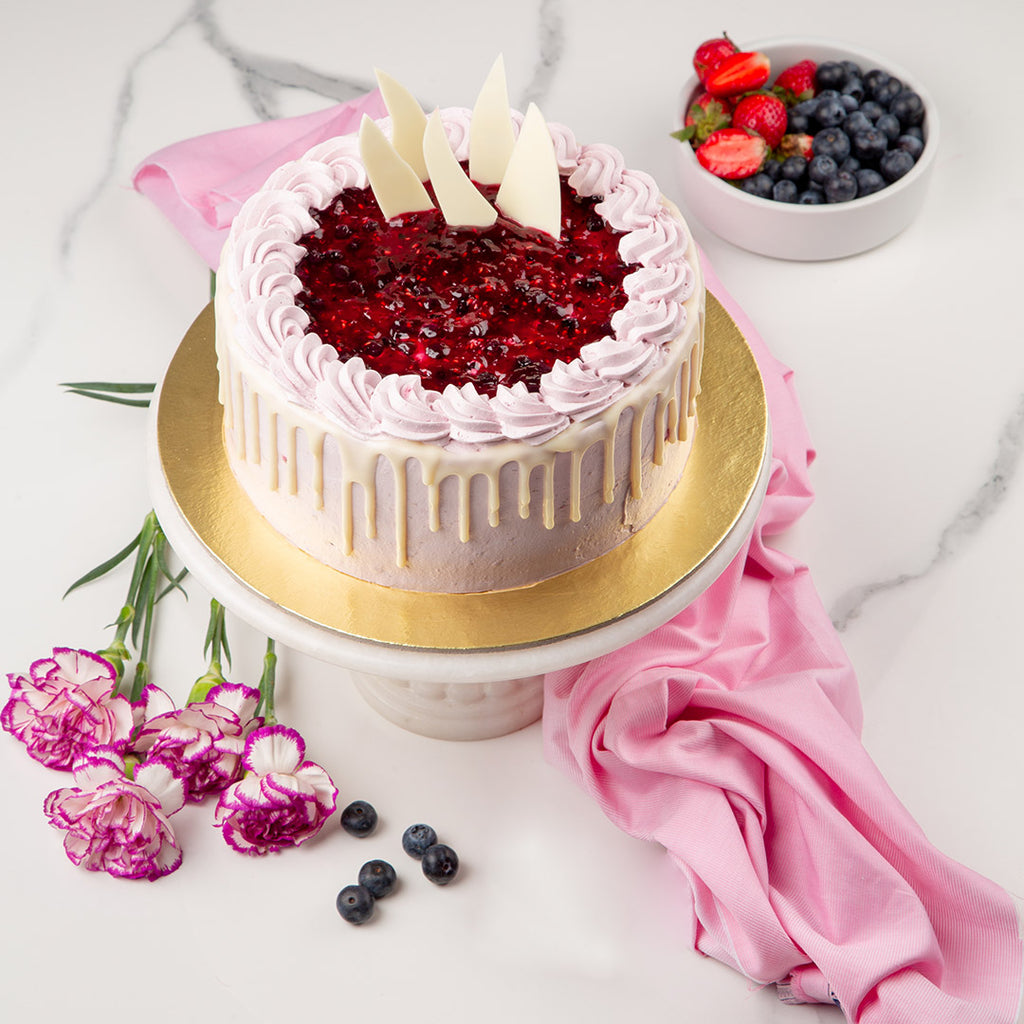 Vanilla berry melange cake is a classic berry cake with fruit compote on top of the cake with white chocolate drips on cake 