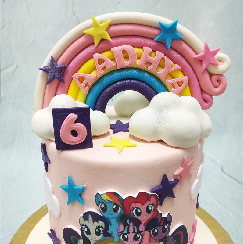 A big, three-dimensional rainbow crowns the top of this My Little Pony birthday cake for kids cushioned by the two clouds on either side of it and in colours complimentative to the cast of the show which can be seen recreated in a poster-like format on the centre of this My Little Pony cake design.