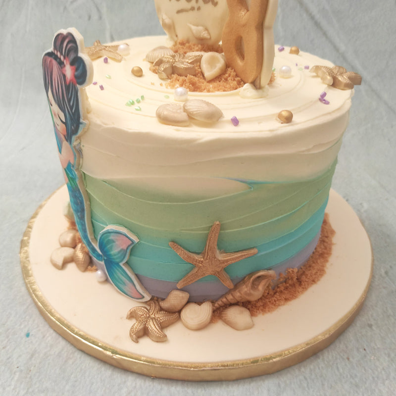 The highlight of this ombre mermaid cake is the artistic figurine of a pretty, little mermaid hugging a sea turtle, both created in an edible poster or placard-like form. The aesthetic of this ombre buttercream mermaid cake splashes longing for the beach into our hearts and onto our taste buds.