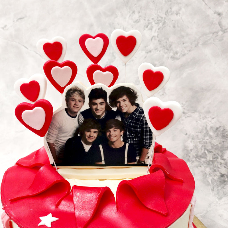 As far as one direction cake ideas go, this piece was designed to be every teenager girl's fantasy feast…. From the hearts to the band to the base which comes in a plain white shade, decorated with embossed edible ribbons framing it vertically. 