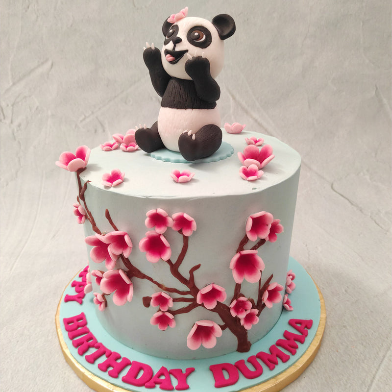The base of this Panda theme birthday cake for kids comes in a beautiful shade of pastel blue with beautiful cherry blossoms blooming all over on their chocolate vines, bringing the oriental aesthetic into the design wholly.