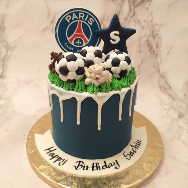 With a matte blue base and a creamy white frosting drip pattern, this PSG theme cake follows the colour theme of the club. It's topped with some footballs and chocolates that look like mud-covered rocks. Along with the green grass that's piped on, the top of this Paris Saint Germain cake resembles a football field. 