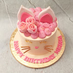 The body of this pink kitty cake features a plain, tall, white base embellished with gold whiskers and eyelashes turned upwards in a way that looks like the cat is smiling. A pink heart-shaped, button nose resides at the centre of this cat theme cake completing the friendly feline look.
