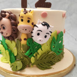 This Safari theme cake design is embellished with different shades of green leaves and the heads of caricature-like, wild animals sticking out of these buttercream bushes. From a lion to a zebra to a giraffe, we have recreated a theme very similar to Madagascar, the animated feature film. 