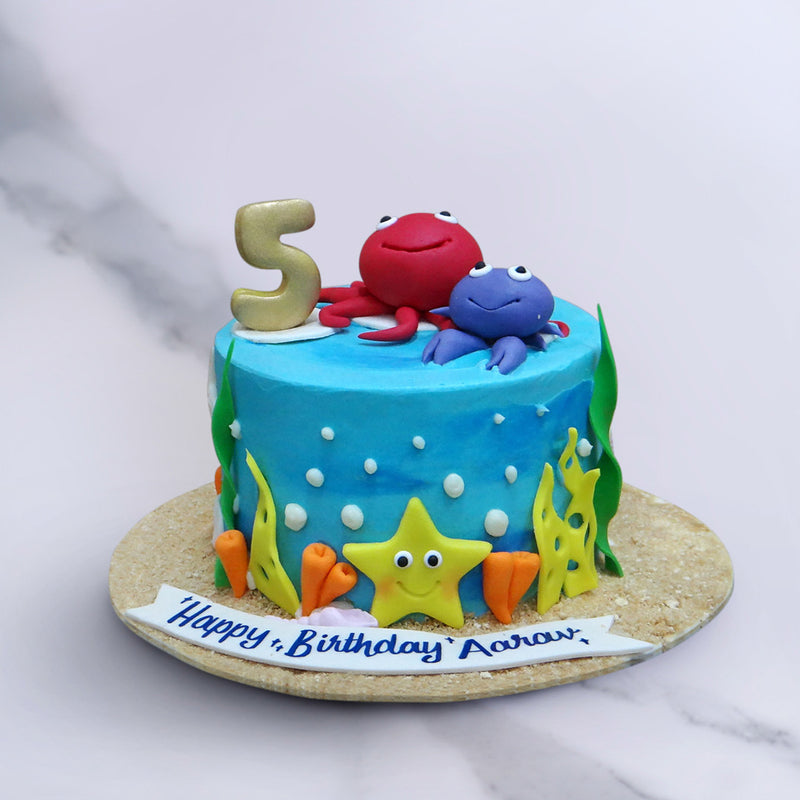 Sea theme cake with crabs on top of the cake and sea shella and star fish on side of the under water theme cake 