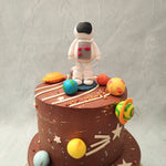 This space themed 1st birthday cake for kids comes in a two tier design. Both are covered in rich and delicious chocolate buttercream showcasing edible models of all the planets and stars in our solar system. The space themed cake decorations also comprise a rocketship that is sailing past the Milky Way.