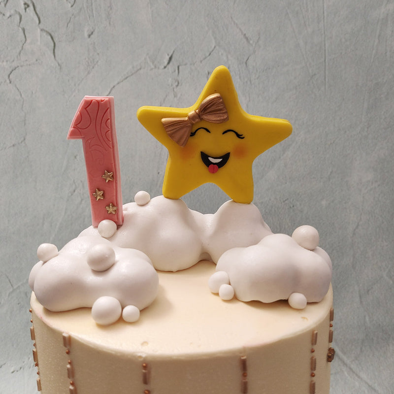 An eye-catching golden bow sits delicately in between both tiers of this twinkle twinkle little star theme cake and the bottom of both tiers are also draped in the same shimmery, gold ribbon.