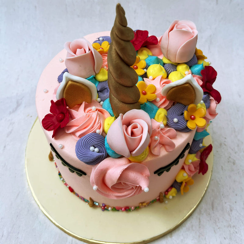 Miniature light yellow and blue meringue peaks fill in the gaps between the swirls, adding to the layers of color and texture in this pink unicorn cake. 