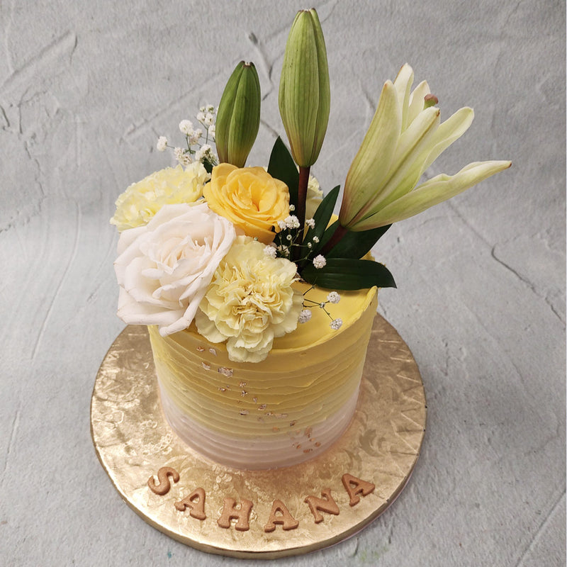The tall, textured base of this yellow flower birthday cake for kids and adults features a sunny yellow to clear white gradient that will remind you of a picnic in the park on a clear-skied, sunny day. The velvety-smooth texture of the buttercream can be seen in every line of the yellow flower cake's texturing. 